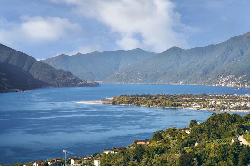 Aerial view of lake and mountains, residential area in foreground, boat on lake