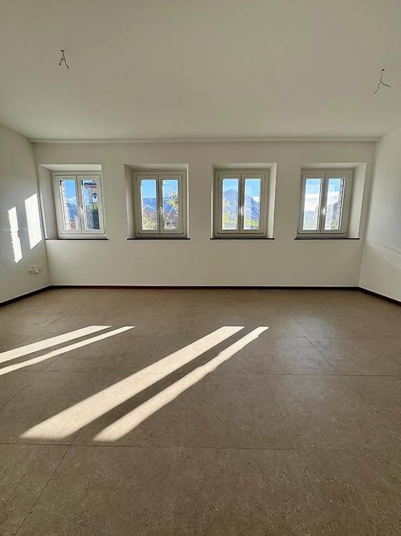 Empty room with white walls, tile floor, four large windows, and view
