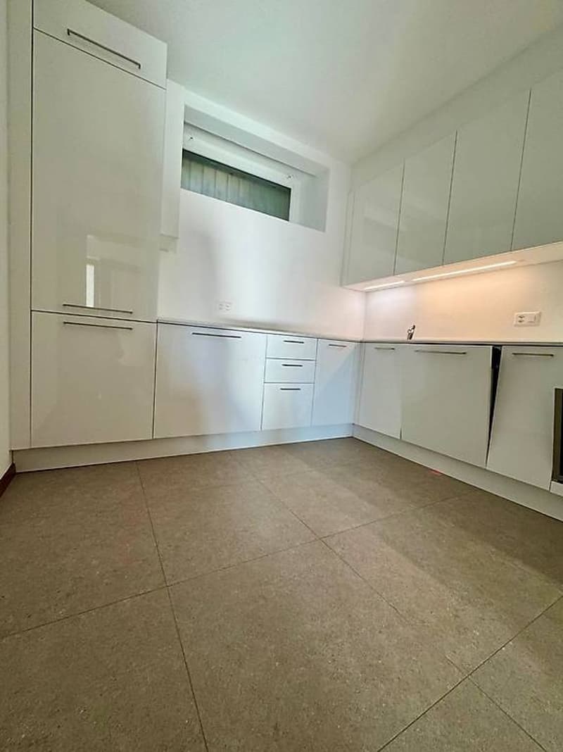 modern kitchen with white cabinets, tiled floor, and sleek countertops