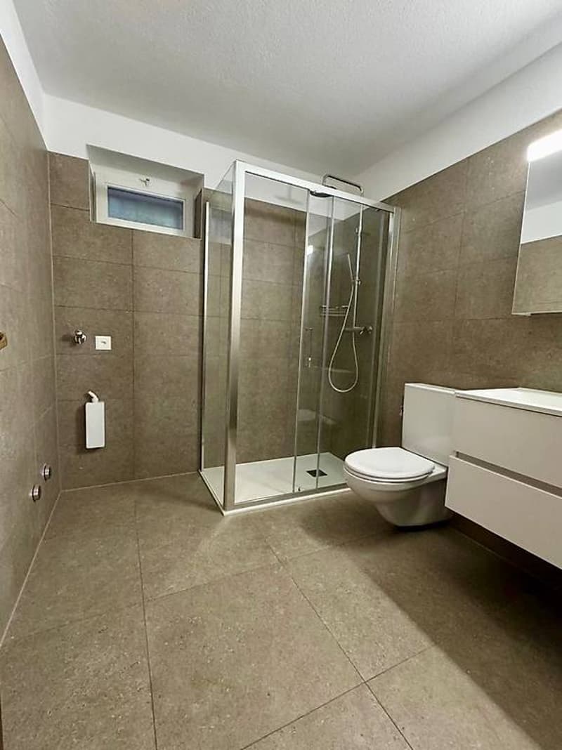 modern bathroom with walk-in shower, toilet, sink, and tiles on the walls and floor