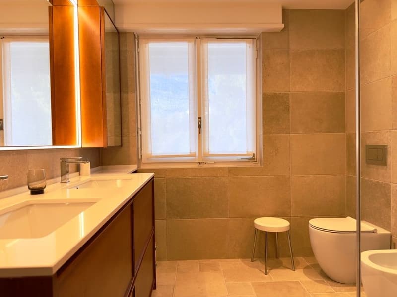 modern bathroom with double sink, wooden cabinets, shower, toilet, bidet, window with blinds
