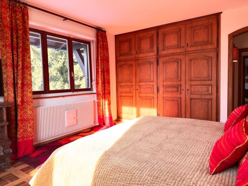 large bed, wooden wardrobe, radiator, carpet, window with curtains, view of trees