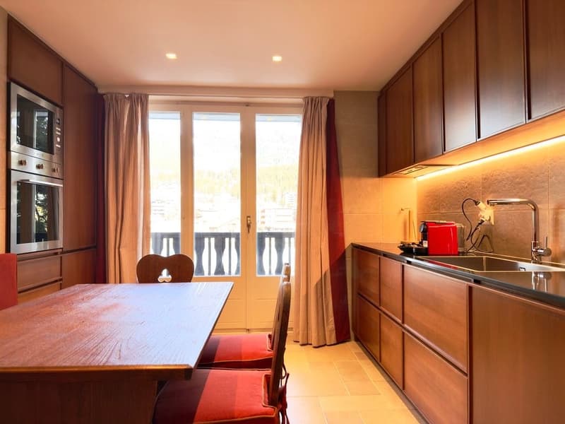 modern kitchen with wooden cabinets, dining table, chairs, microwave, oven, sink, faucet, balcony with railings, large windows