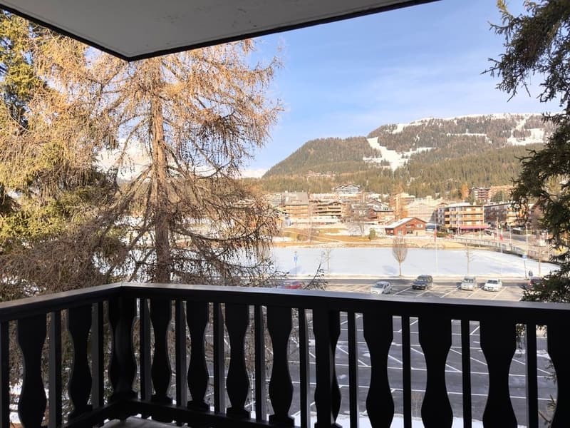 balcony with railings, view of a parking lot, trees, and a mountain