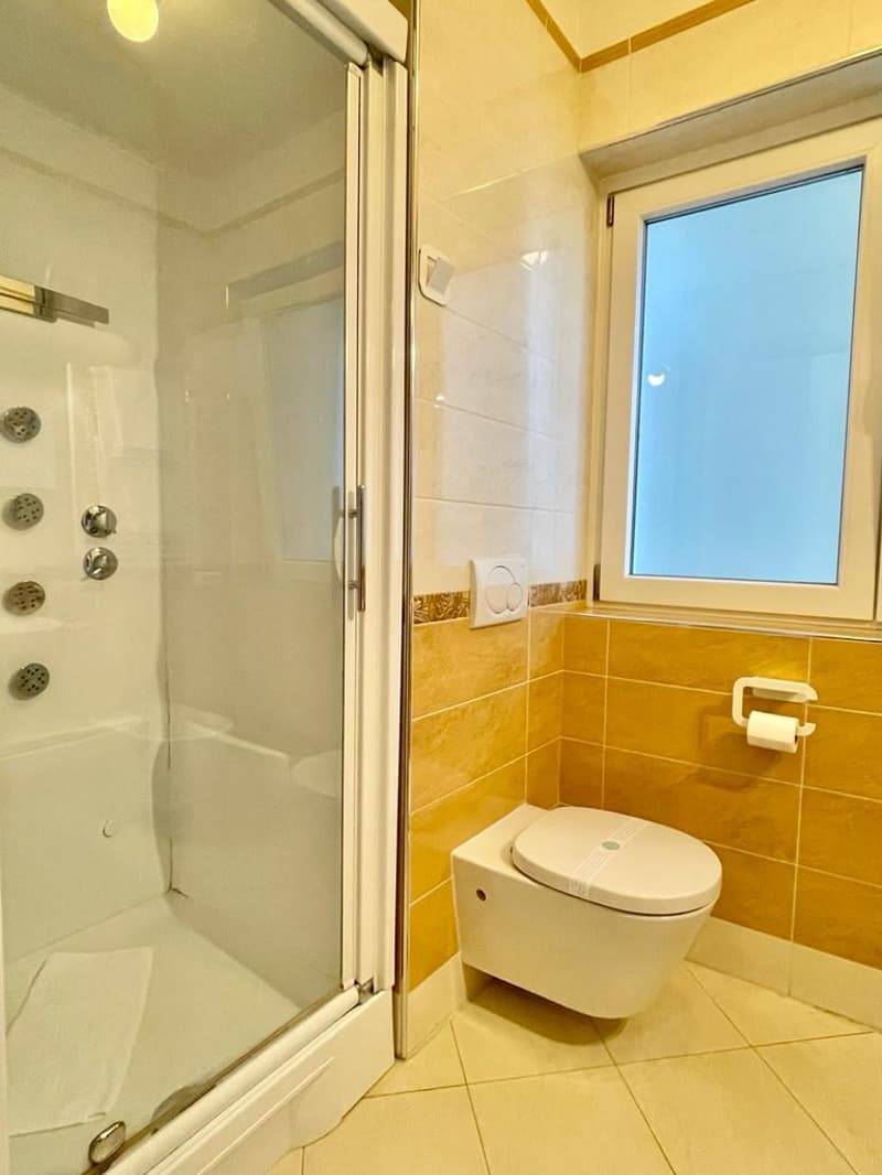 small bathroom, shower, toilet, window, tiled floor, beige tiles