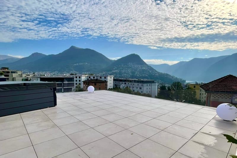 Terrace with tiled floor, two large white spheres, swimming pool, mountains in the distance, cityscape view
