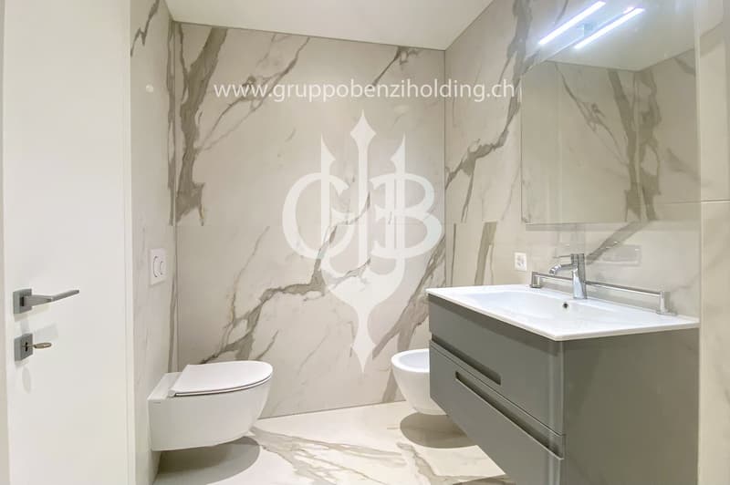 marble walls, toilet, bidet, vanity with sink, large mirror