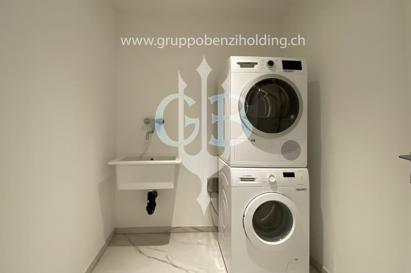 Modern, clean laundry room with a white sink, Bosch washing machine and dryer, and marble flooring.
