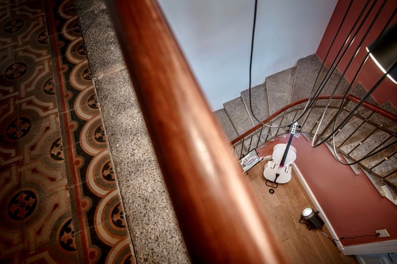 top view of the staircase, polished wooden floor, painted walls, white cello with stand, floor lamp