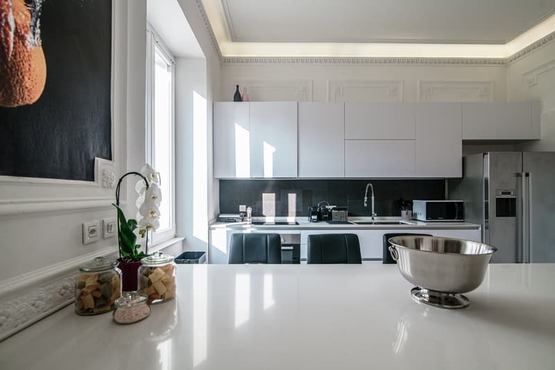 modern kitchen, white cabinets, granite countertops, stainless steel refrigerator, oven, gas stove, microwave, sink, white flooring, decorative jars