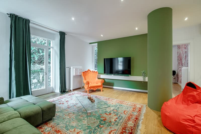 large sofa, carpet, TV, glass coffee table, orange armchair, green walls