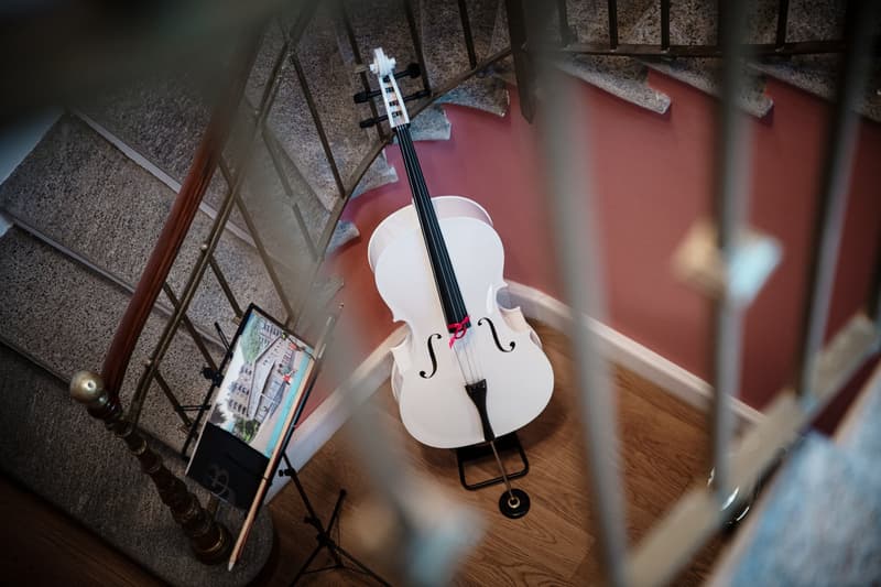 staircase, white cello on a stand, music sheet stand