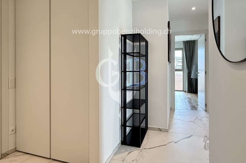 wide hallway, white walls, marble floor, large mirror, black open shelving, open doorways