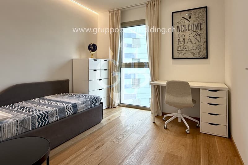 single bed, desk with chair, drawers, large window, white walls, wooden floor