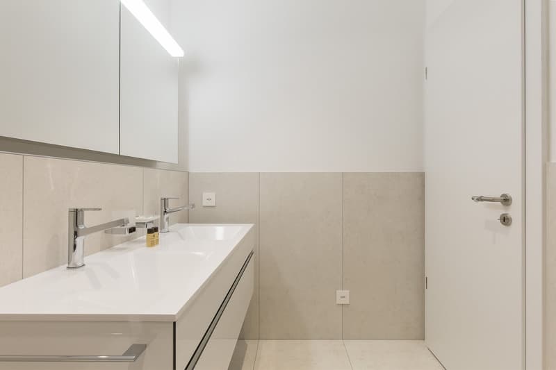 modern white vanity, double sink, mirror, dual faucets, soap dispensers, white tiles, minimalistic