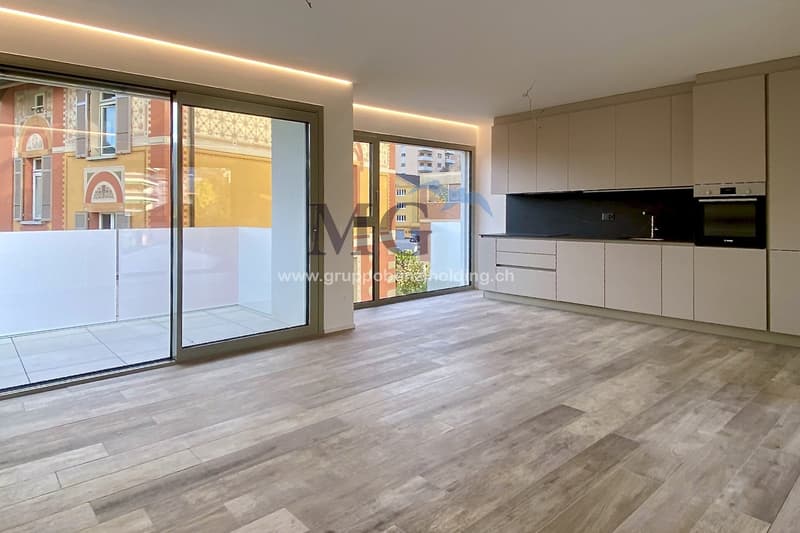 open plan living room and kitchen, large windows, sliding glass doors to terrace
