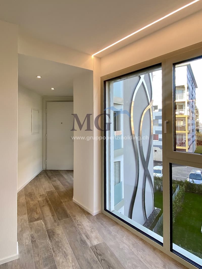 corridor with wooden floor, large windows, and bright room