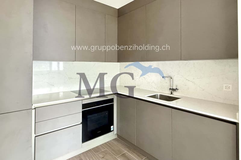 Modern minimalist kitchen, white marble countertops, stainless steel sink and faucet, black integrated oven and stovetop, wooden floor, gray cabinets and drawers