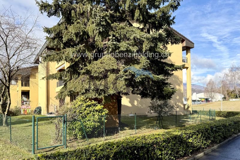 yellow facade, fence, bush, tree, two balconies