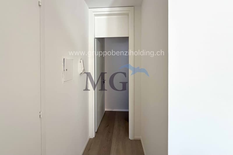 empty hallway, wooden flooring, white walls, open door to another room, doorway