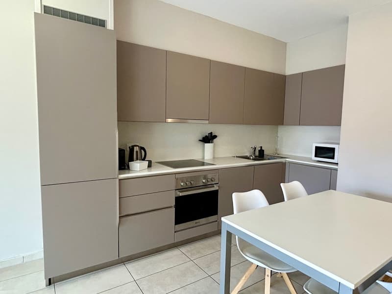 modern kitchen with white tiles, gray cabinets, white countertop, built-in oven, microwave, sink, and faucet