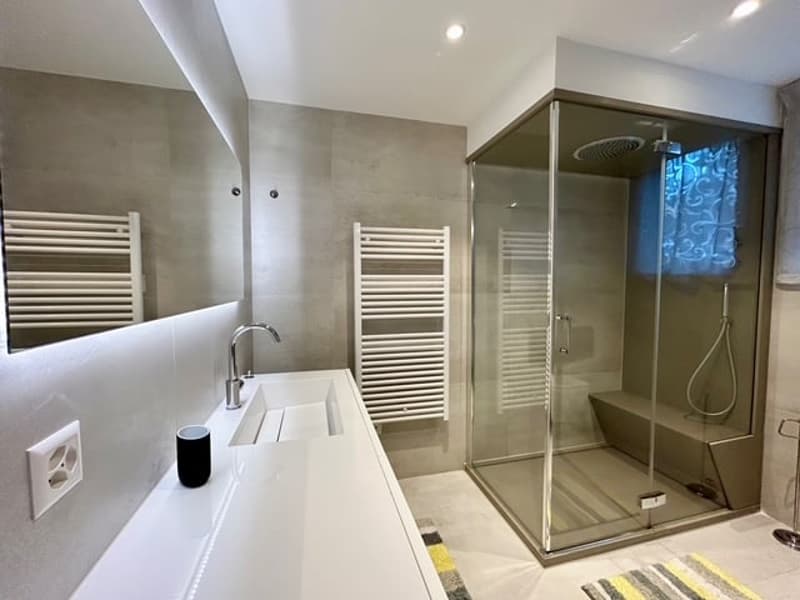 Modern bathroom, white sink, glass shower stall, wall-mounted towel rack, wall-mounted power outlet, shower head