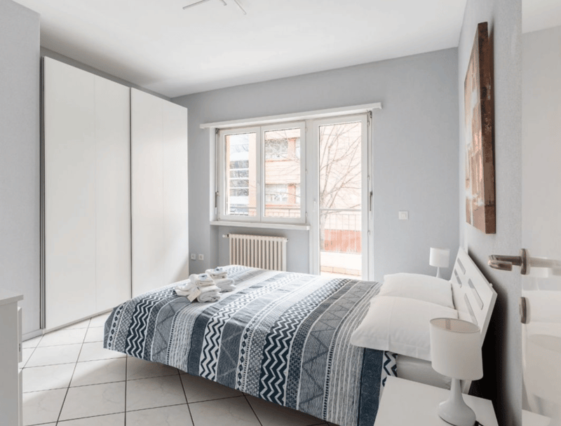 bedroom with bed, bedside tables, lamps, closet, window