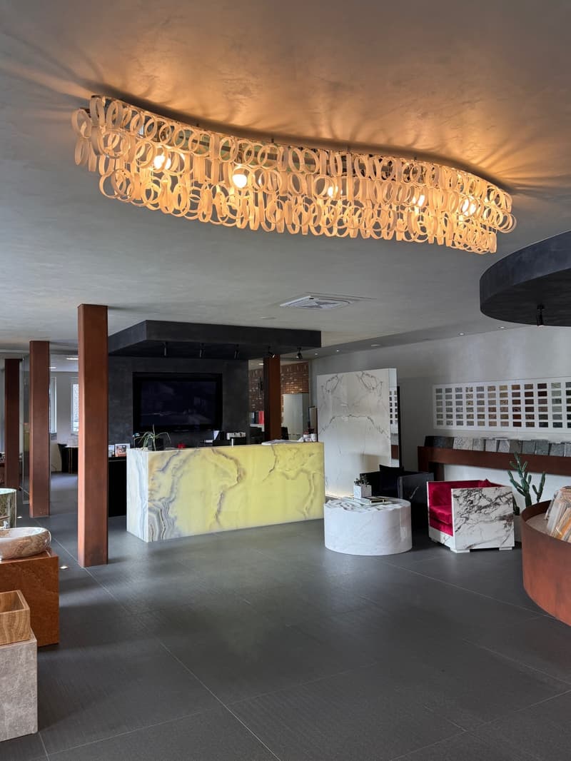 A spacious lobby area with a large circular chandelier, a counter, and a large television.
