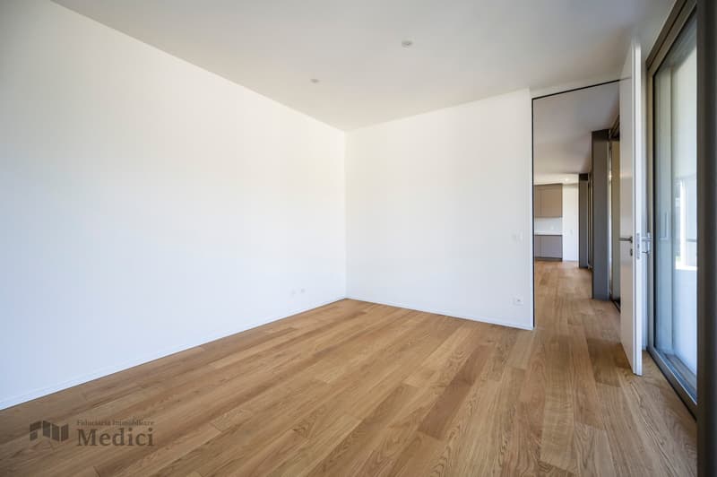 modern clean room with hardwood floors, glass door leading to another room, and light white walls