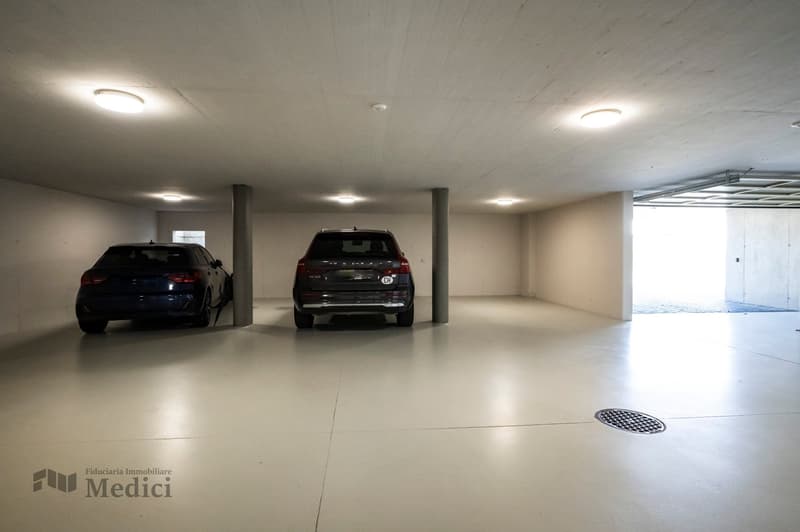 Underground garage, 2 cars parked, 2 ceiling lights, small drainage hole