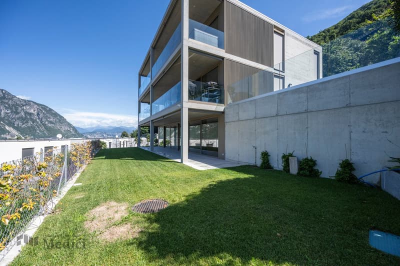 modern multistory residential building, concrete exterior, multiple balconies, large glass windows, grassy lawn