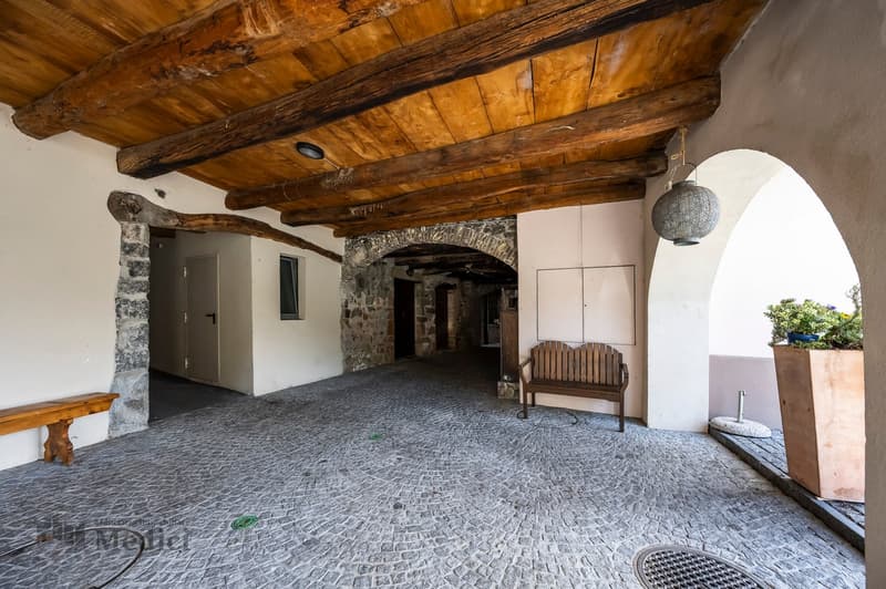 wooden beams, stone walls, bench, arched entryway, cobblestone floor