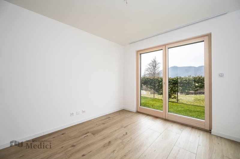 wooden floor, sliding glass door to the outside with a view of the landscape, white walls, empty room