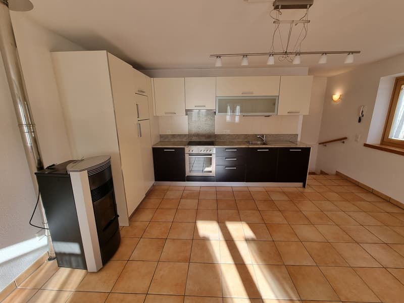 Modern kitchen with white and black cabinets, tiled floor, gas stove, oven, and a fireplace
