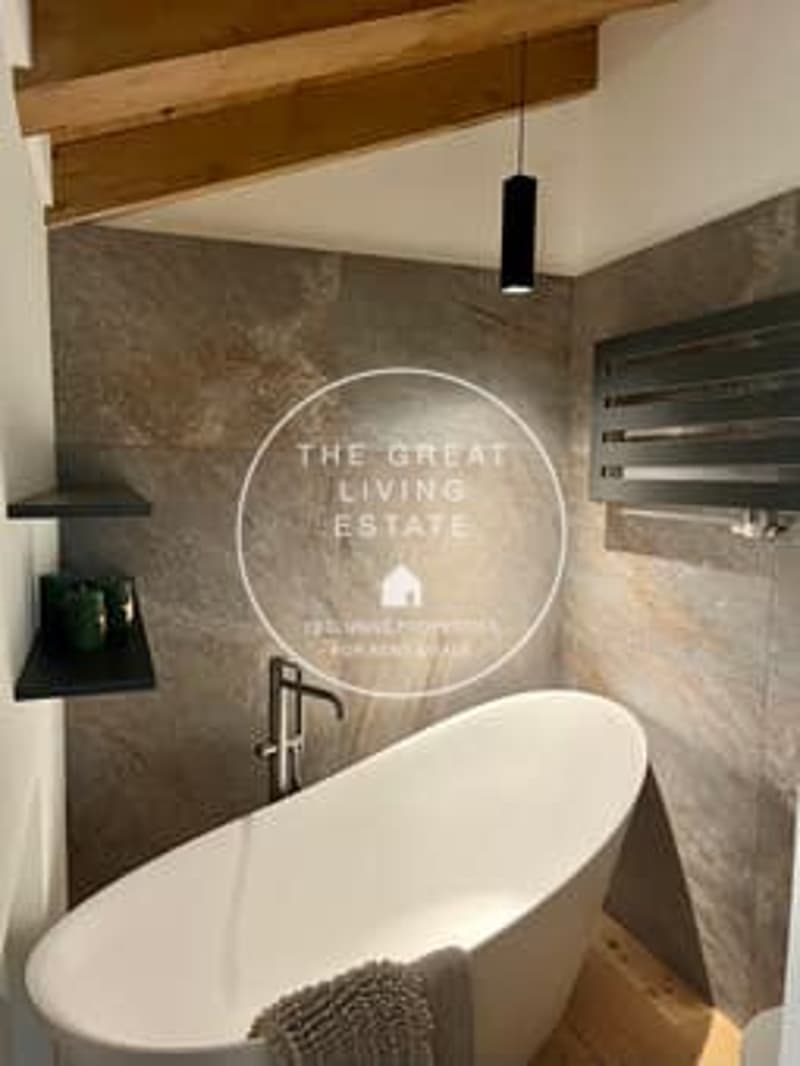 Freestanding bathtub, stone wall tiles, wooden beams, pendant light fixture