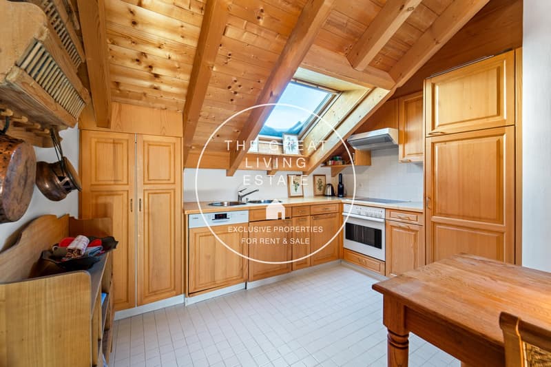 Spacious kitchen with wooden cabinets, wooden ceiling beams, tiled floor, and a fireplace