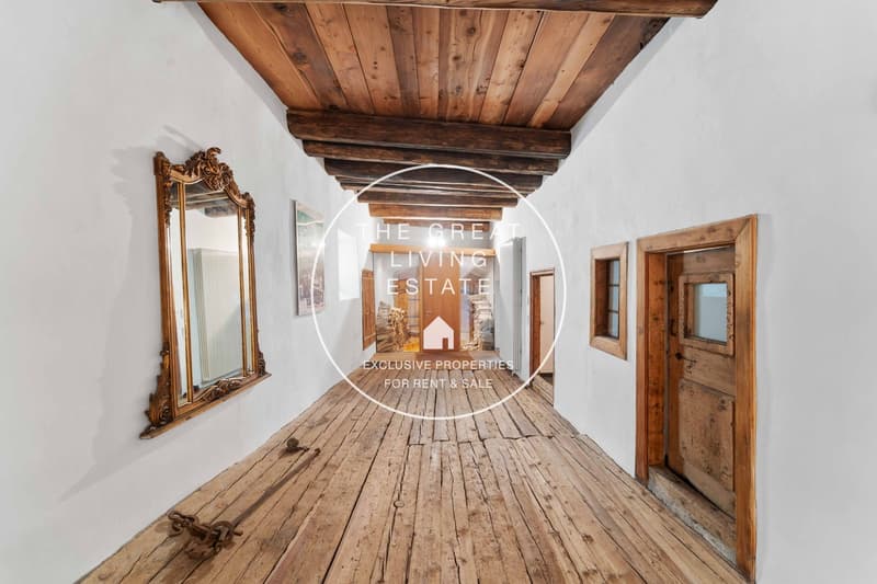 Wooden flooring, wooden ceiling, white walls, ornate mirror on wall, wooden doors, rustic atmosphere