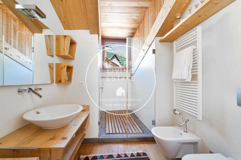 A wooden bathroom with white sink, mirror, shower and toilet.