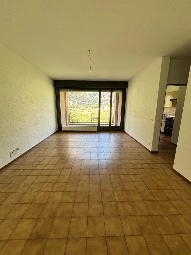 Empty room with tiled flooring, glass doors leading to balcony, white walls, electrical outlets