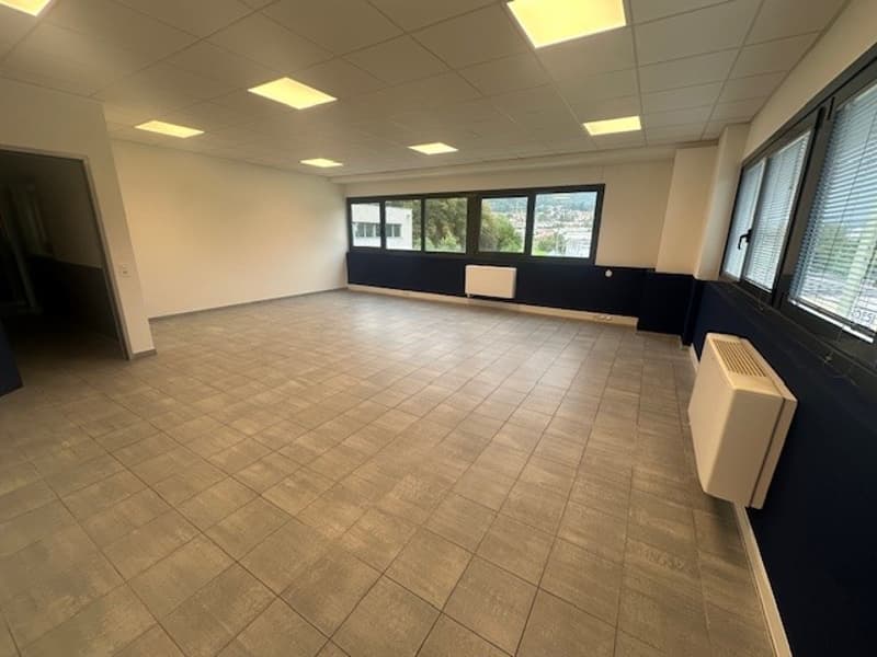 Large open space, tiled floor, white walls, blue accent walls, large windows, built-in radiators, no furniture