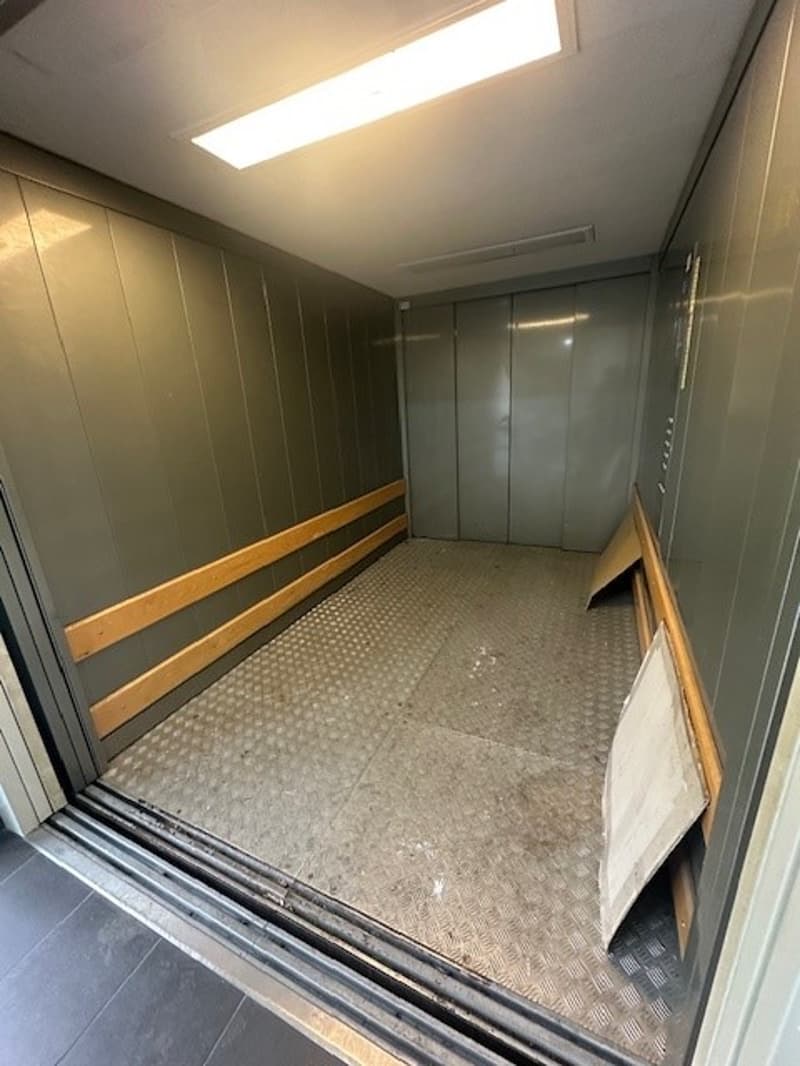 open elevator room, metallic flooring, gray walls, closed metal doors