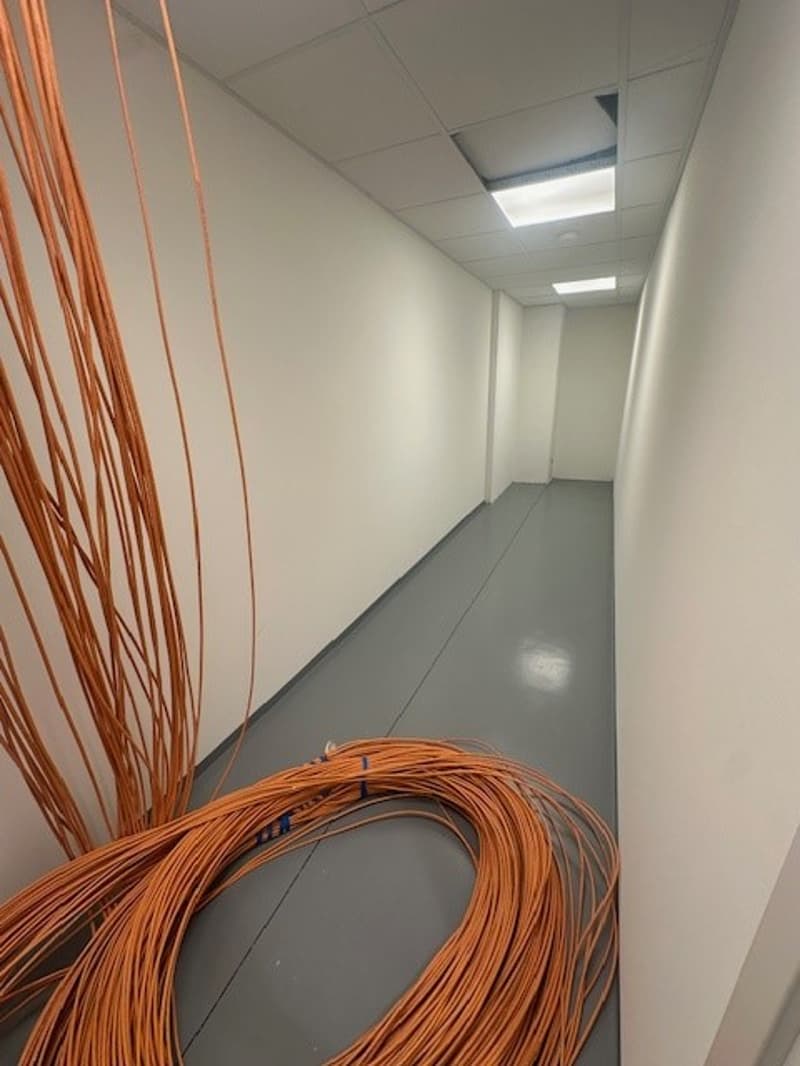 empty corridor, white walls, grey floor, large orange cables