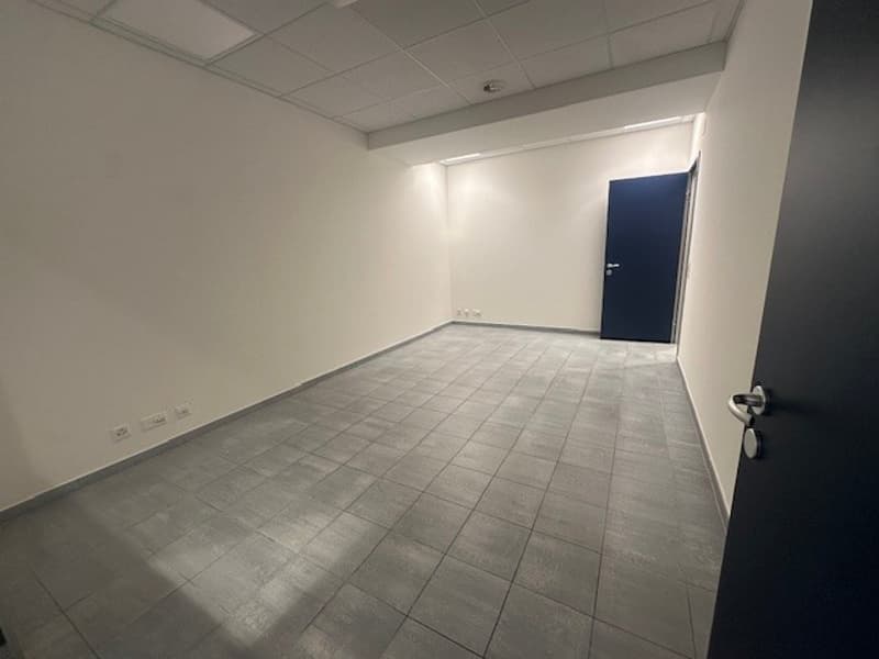 Empty room, white walls, gray tiled floor, blue door, power outlets