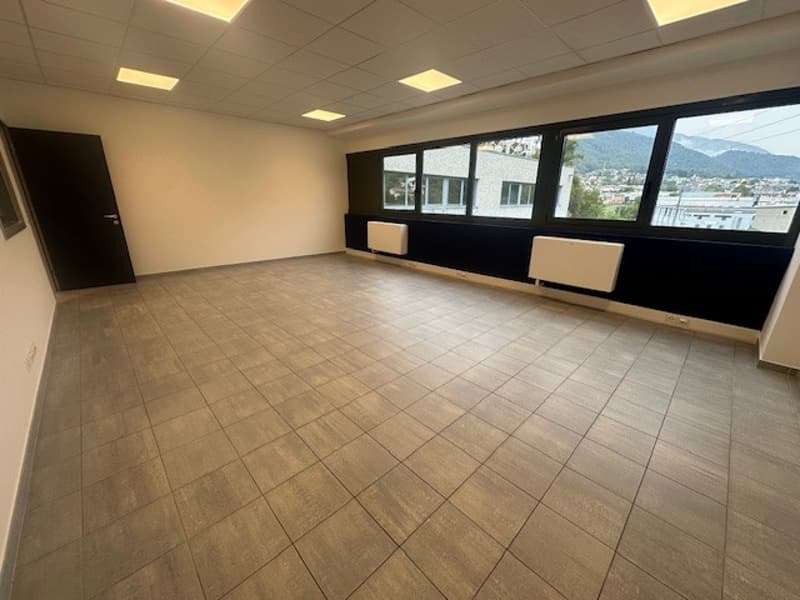 large empty room, white walls, brown tiles, black door, two radiators