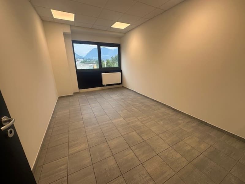 an empty room with brown tiled floor, white walls, large window, radiator