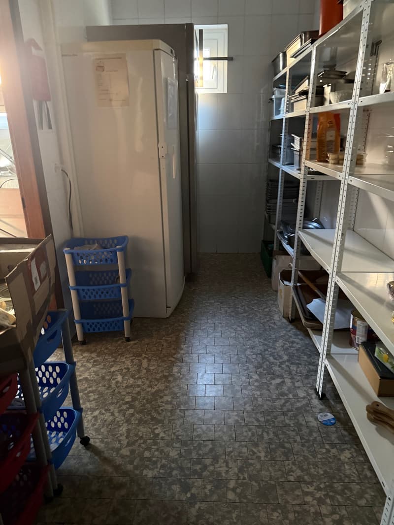 a room with tiled floor, a refrigerator, blue storage racks, metal shelves with boxes and other items, a window
