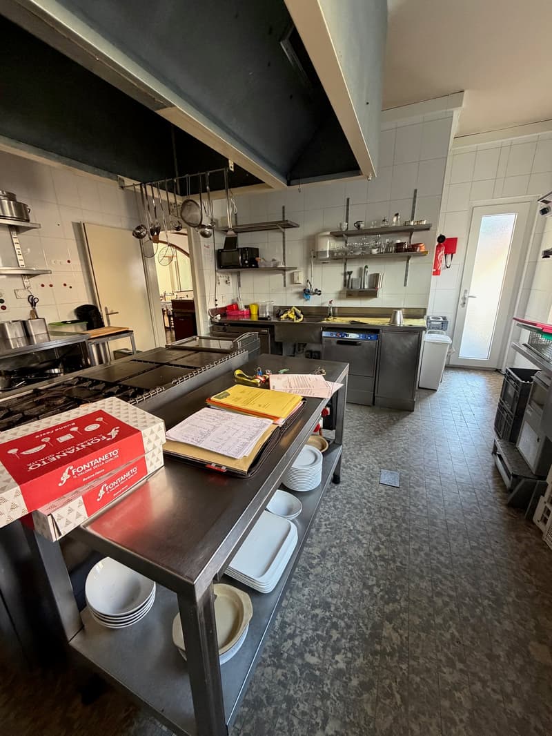 commercial kitchen, stainless steel countertops, gas stove, oven, sink, cabinets, shelves, plates, boxes