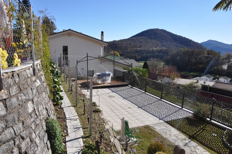 House with a garden, stone wall, metal fence, and a view of the mountains