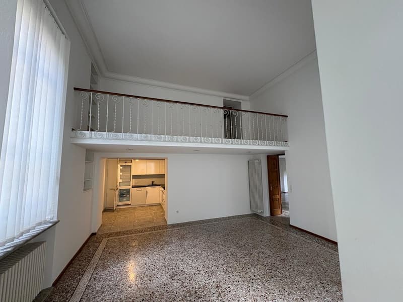 Empty room with marble flooring, balcony with railings, entrance to the kitchen, and heater on the wall