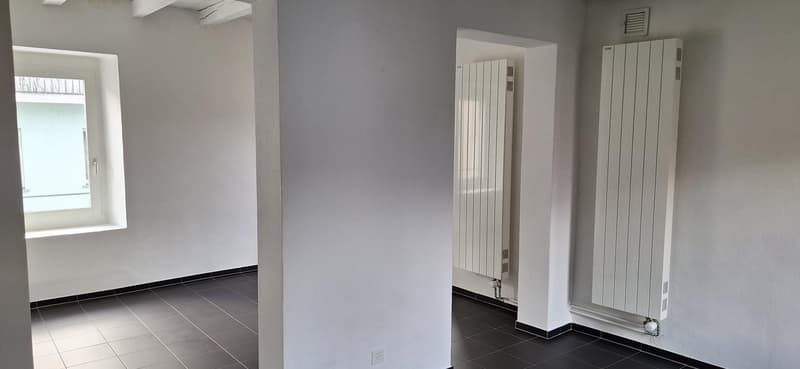 Empty room, white walls, black tiled floor, window, wall-mounted radiators